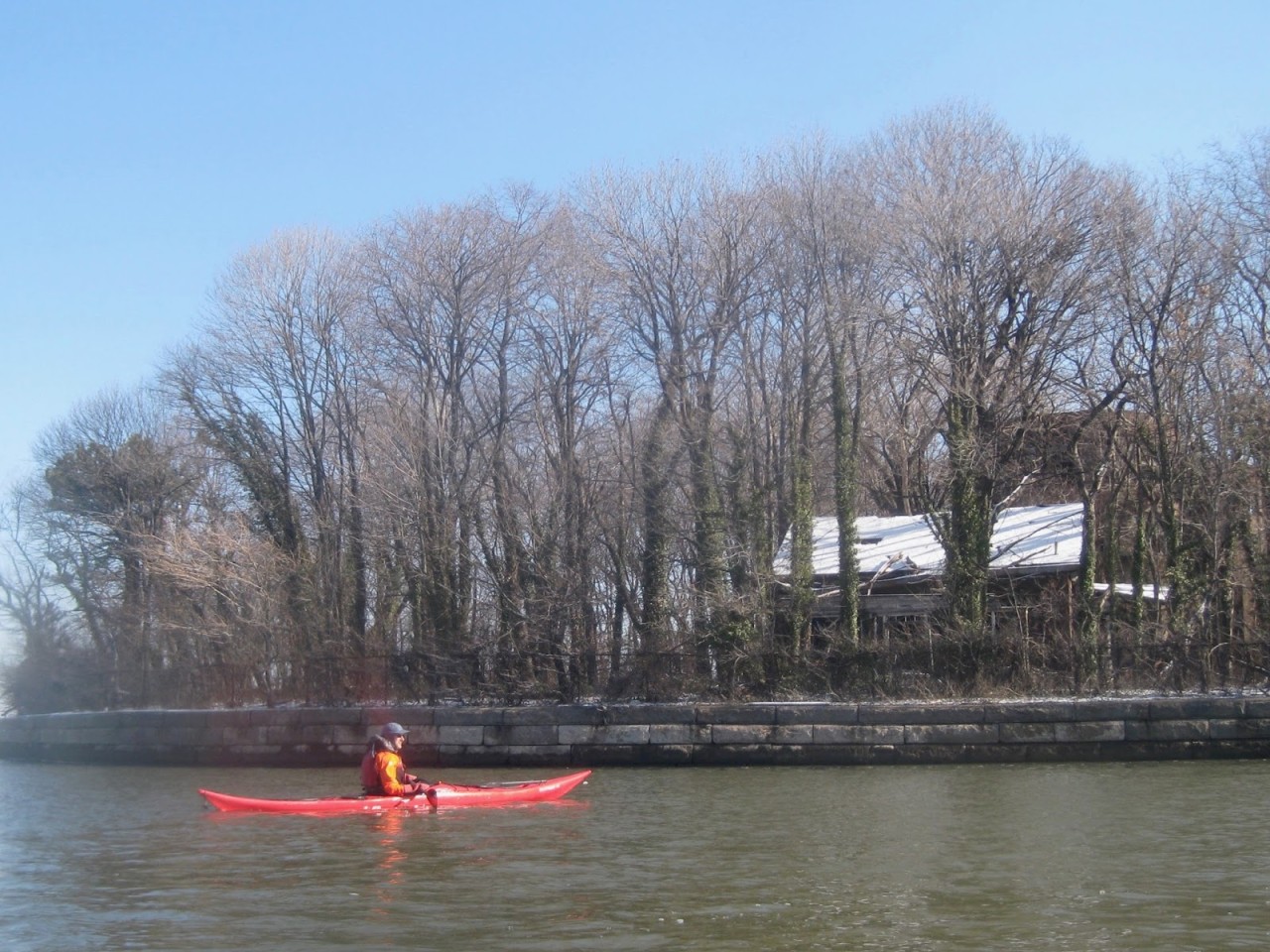 Kayaker at North Brother Island, with the Caretaker's House in disrepair in the background.