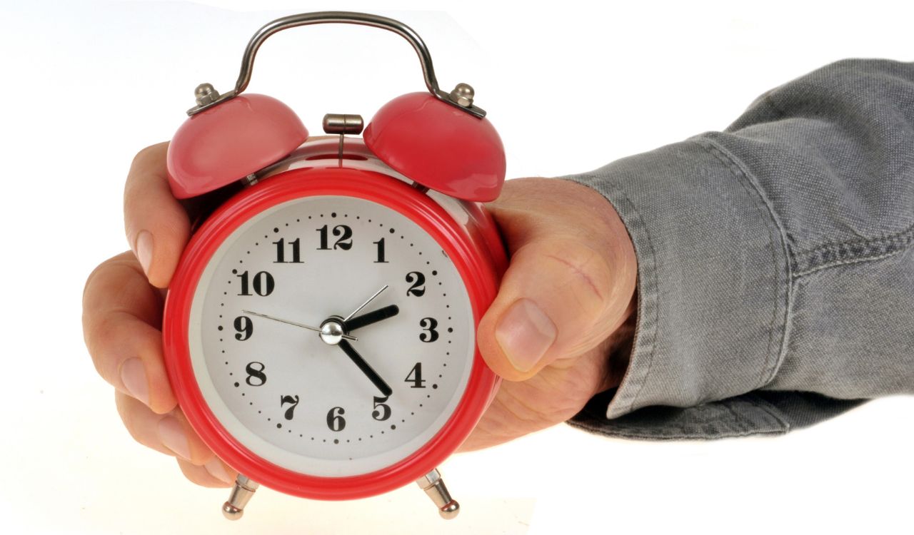 Alarm clock held in hand on white background