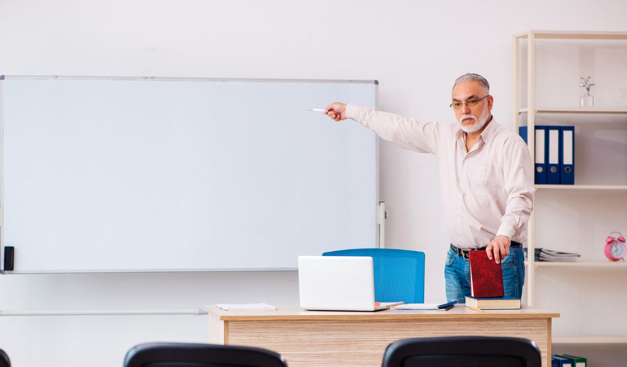 Old male teacher in the classroom in pandemic concept