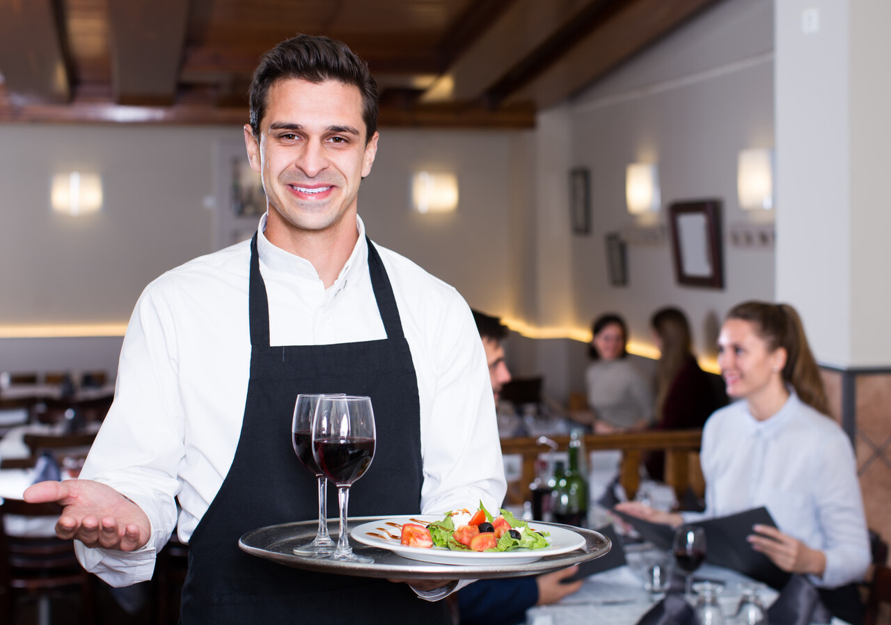 happy waiter with serving tray welcoming to restaurant