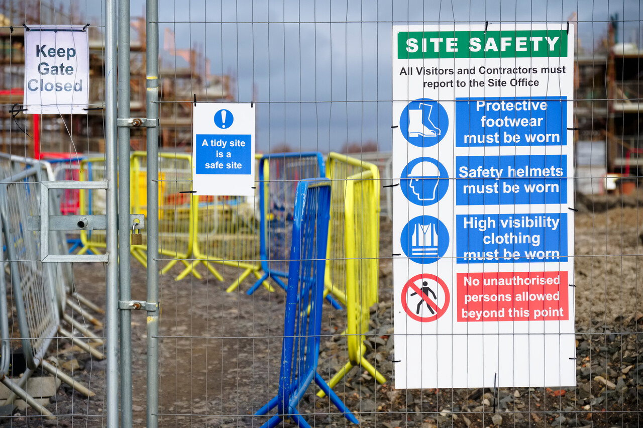 Construction site entrance showing required safety footwear signage and boots placed nearby.