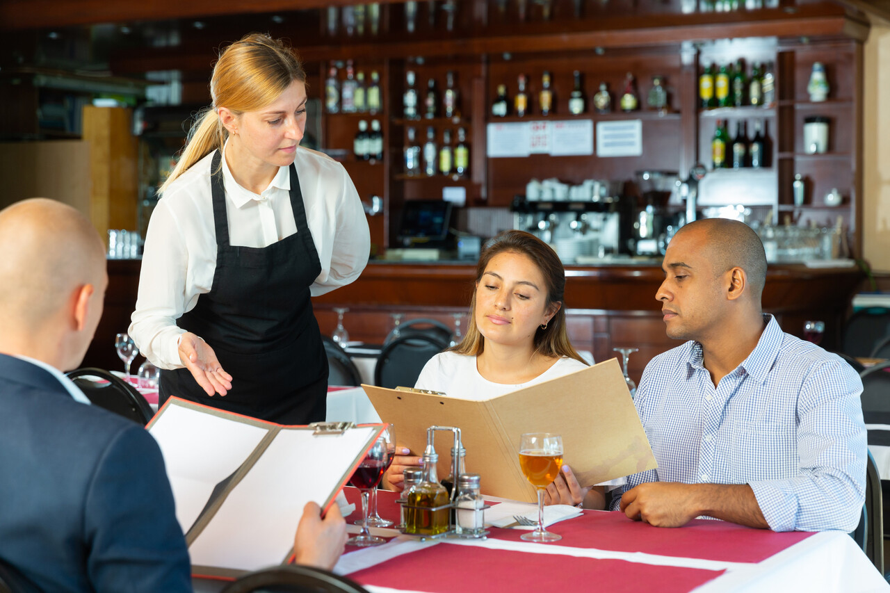 Polite waitress taking order from guests in pizza restaurant