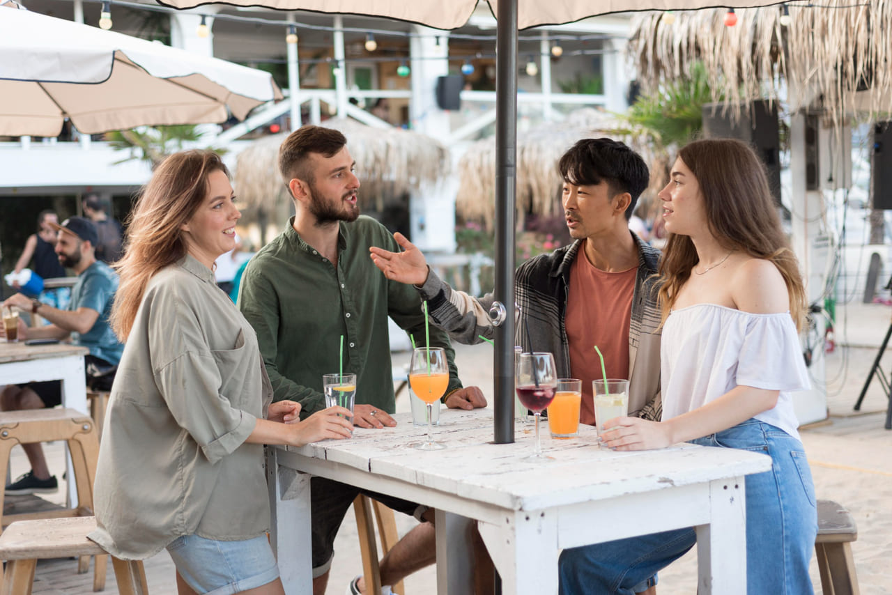 A candid moment of travelers and locals interacting politely in a community setting, such as a market stall or small café.