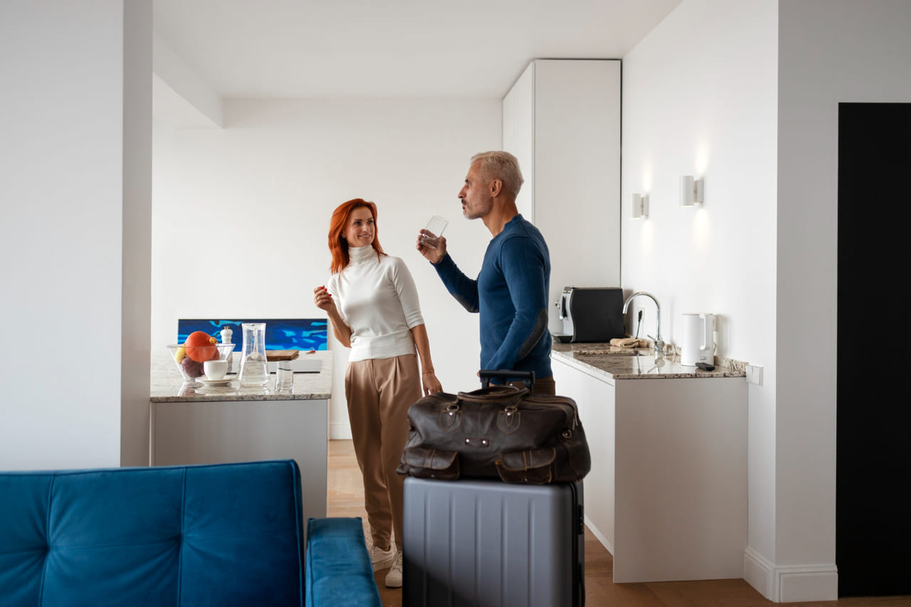 A person returning home with luggage and smiling at a clean, fresh kitchen.