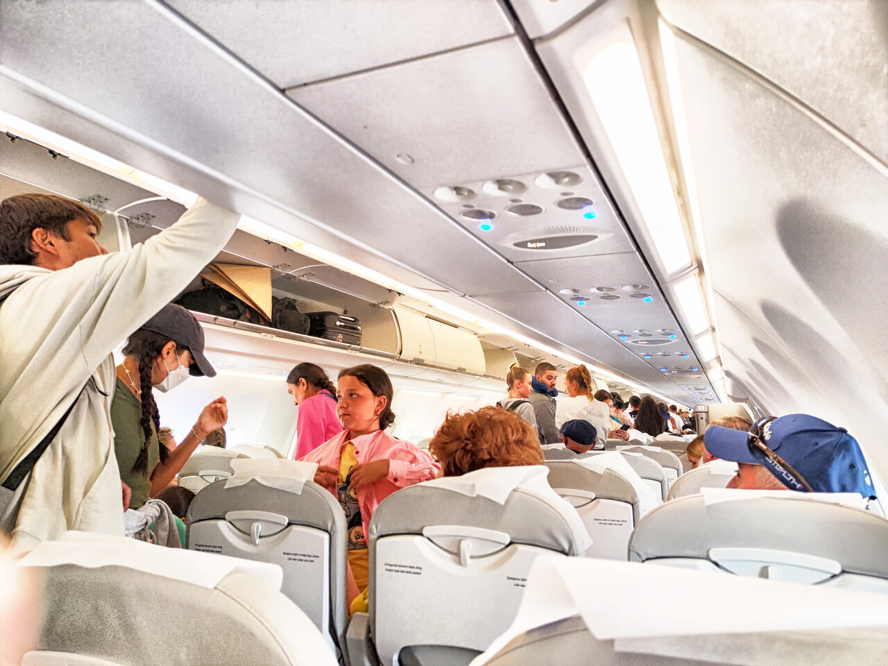 A wide interior shot of a full airplane cabin during boarding
