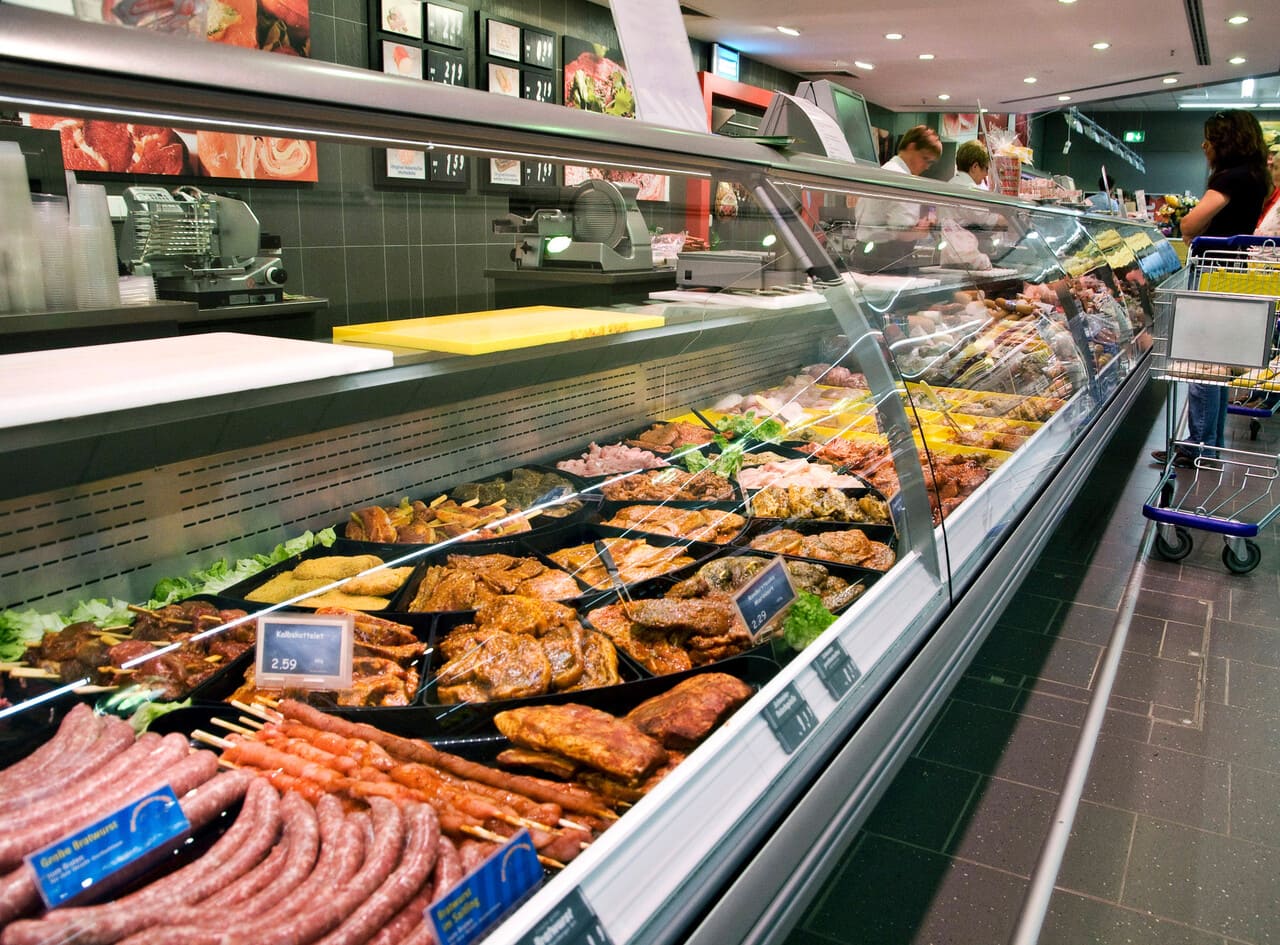 A grocery store cooler featuring plant-based patties next to traditional meat.