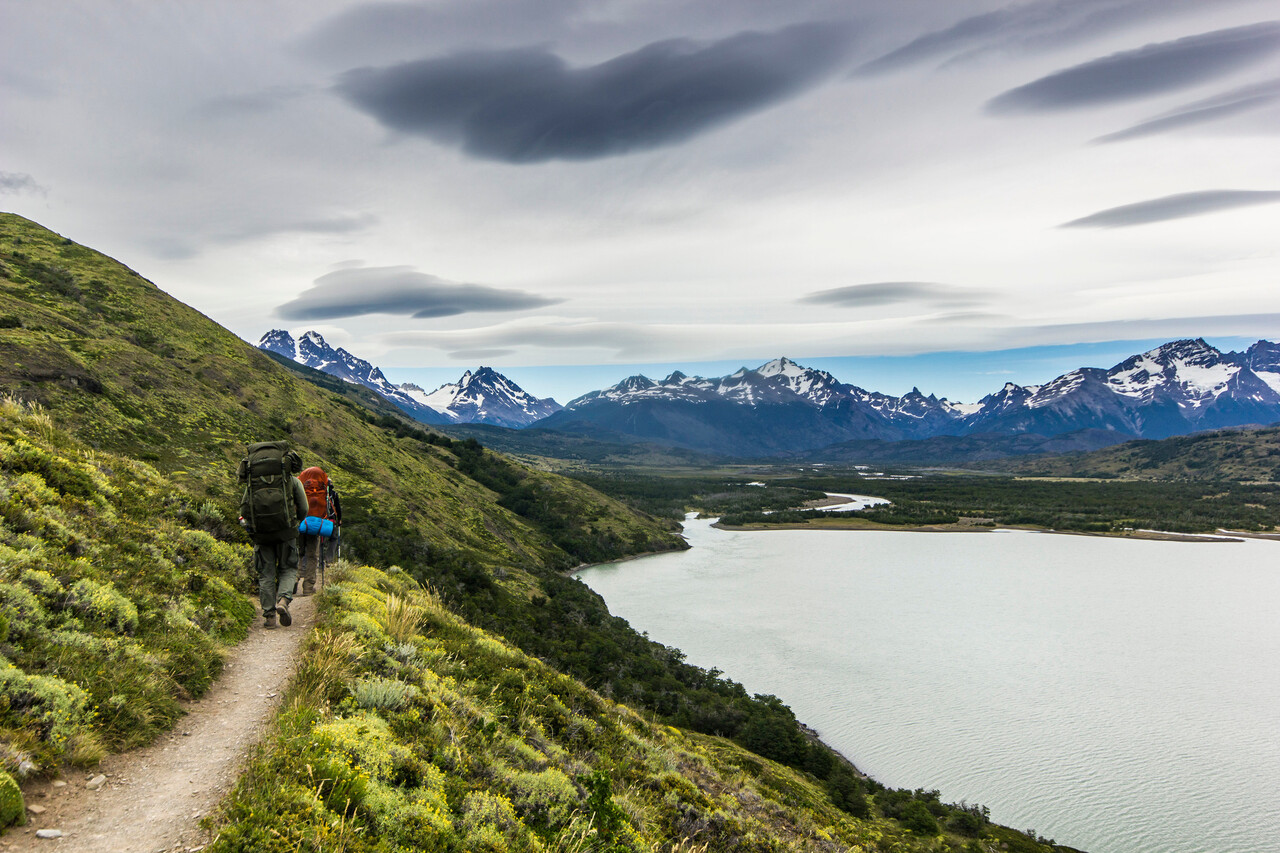 A pair of hikers on a trail with Patagonia’s sharp peaks