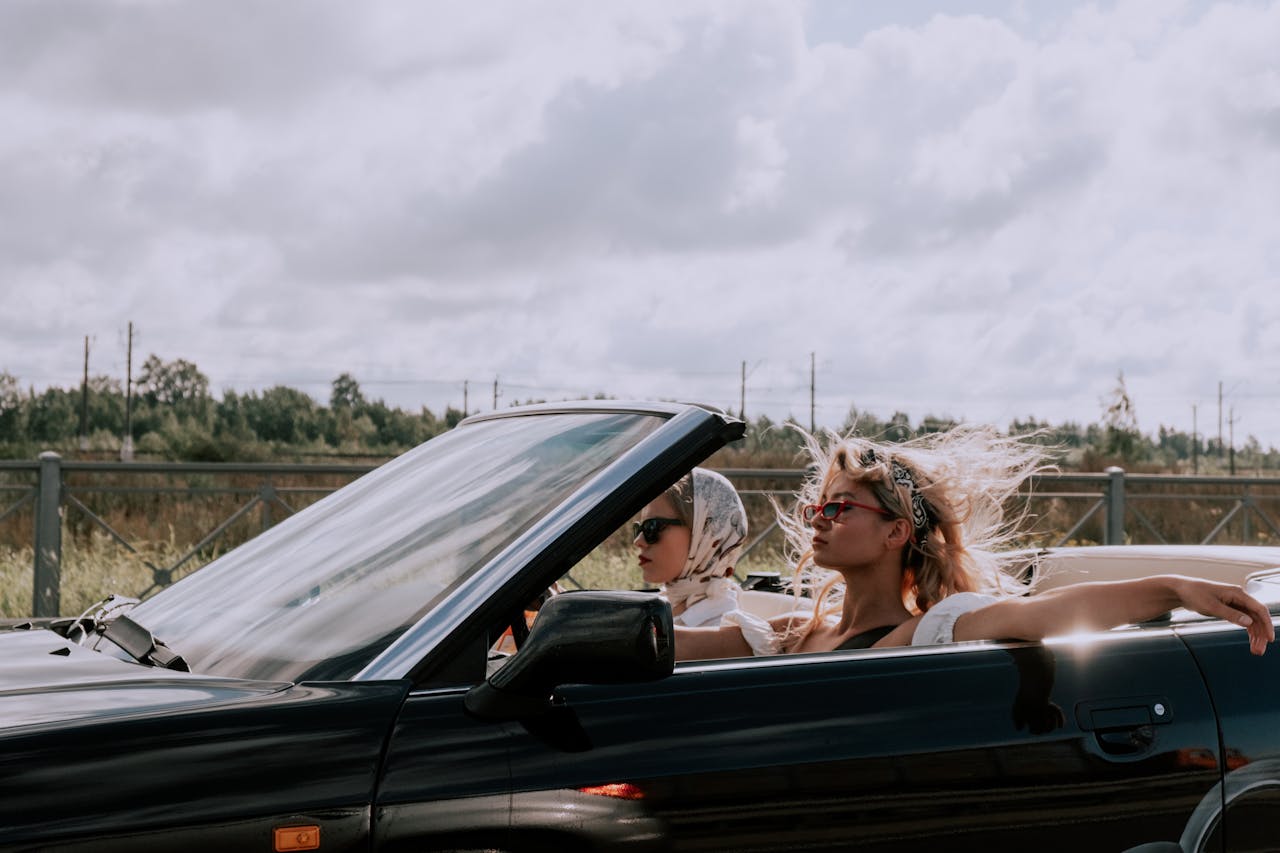 Young adults traveling in separate cars on an open highway,