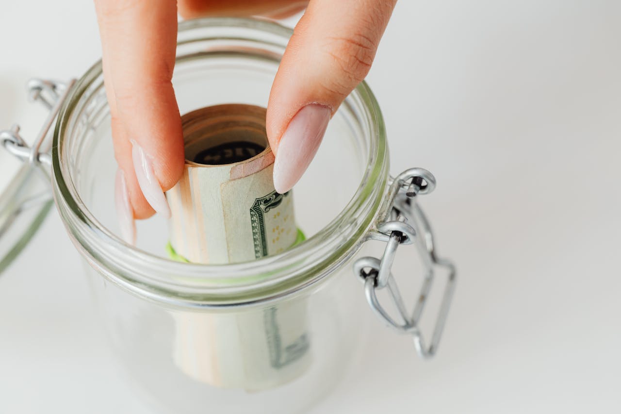 Person moving money from coffee or entertainment budget into a travel jar.