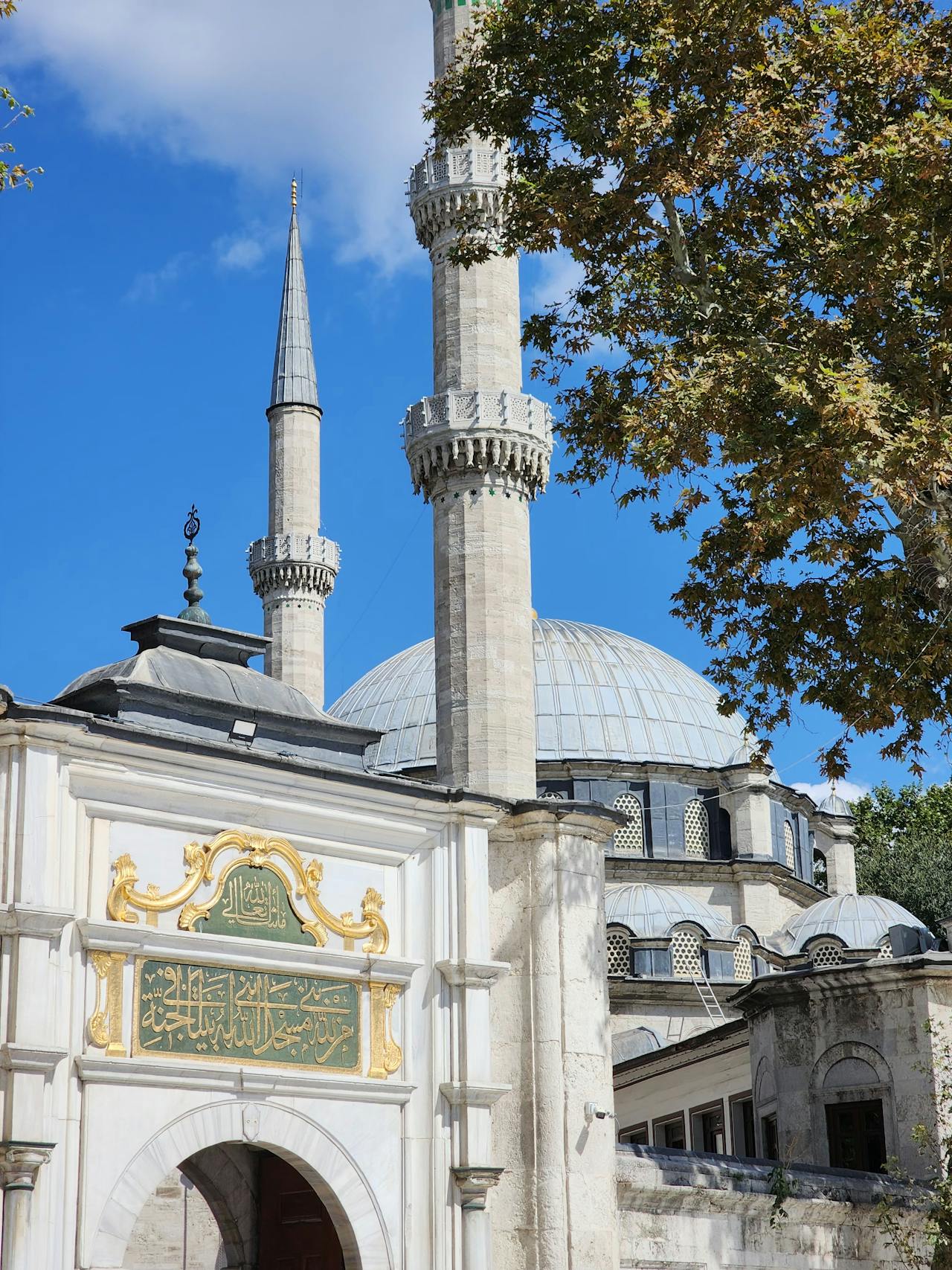 An entrance to a Middle Eastern cultural or religious site with modesty guidelines displayed on a signboard.