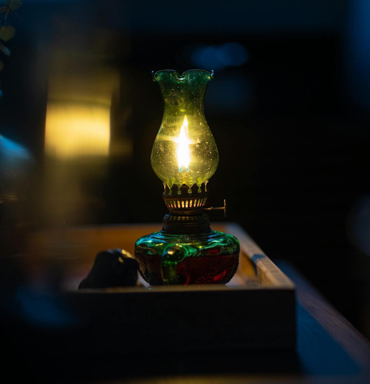An old kerosene lamp glowing in a dark bedroom.