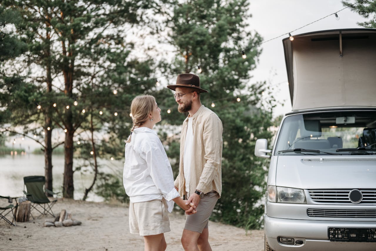 A couple standing near a campervan with New Zealand’s mountains, lakes
