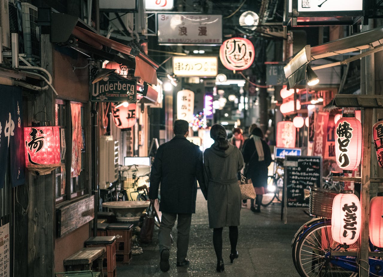 A quiet Japanese street with lanterns, a couple walking past small shops,