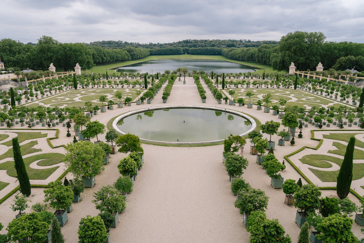 A landscaped French garden with well-kept paths and small signs reminding visitors not to walk on protected grass.
