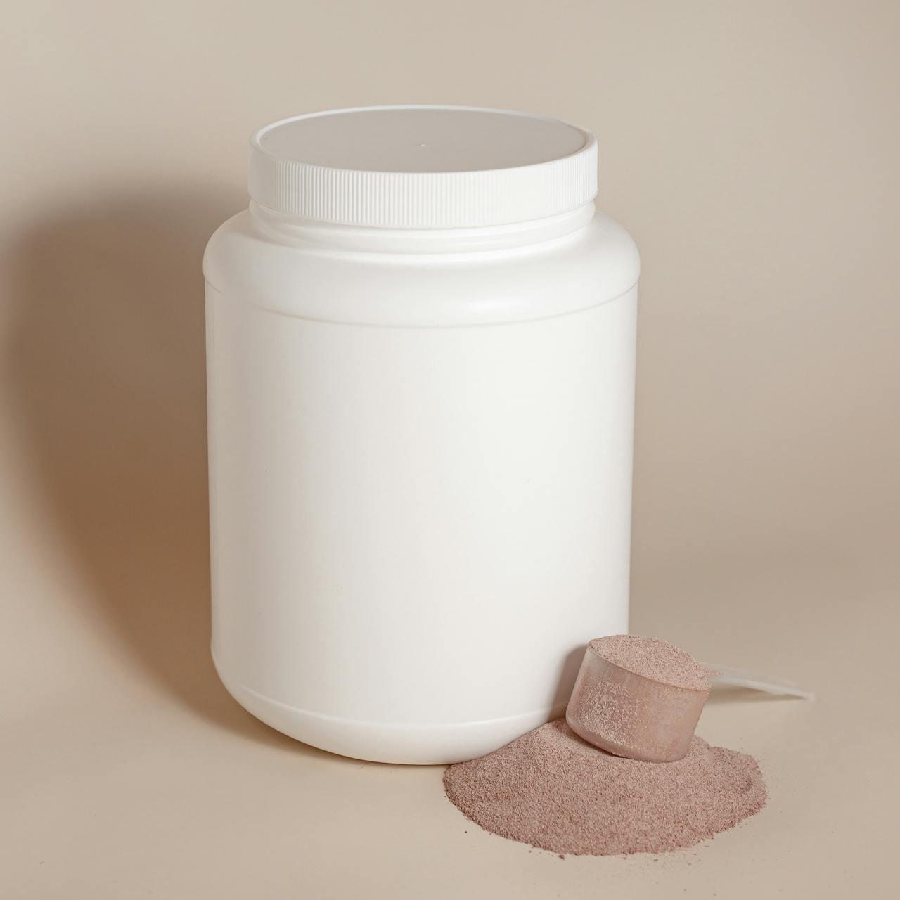 A container of workout powder with a measuring scoop lying dry on the surface.
