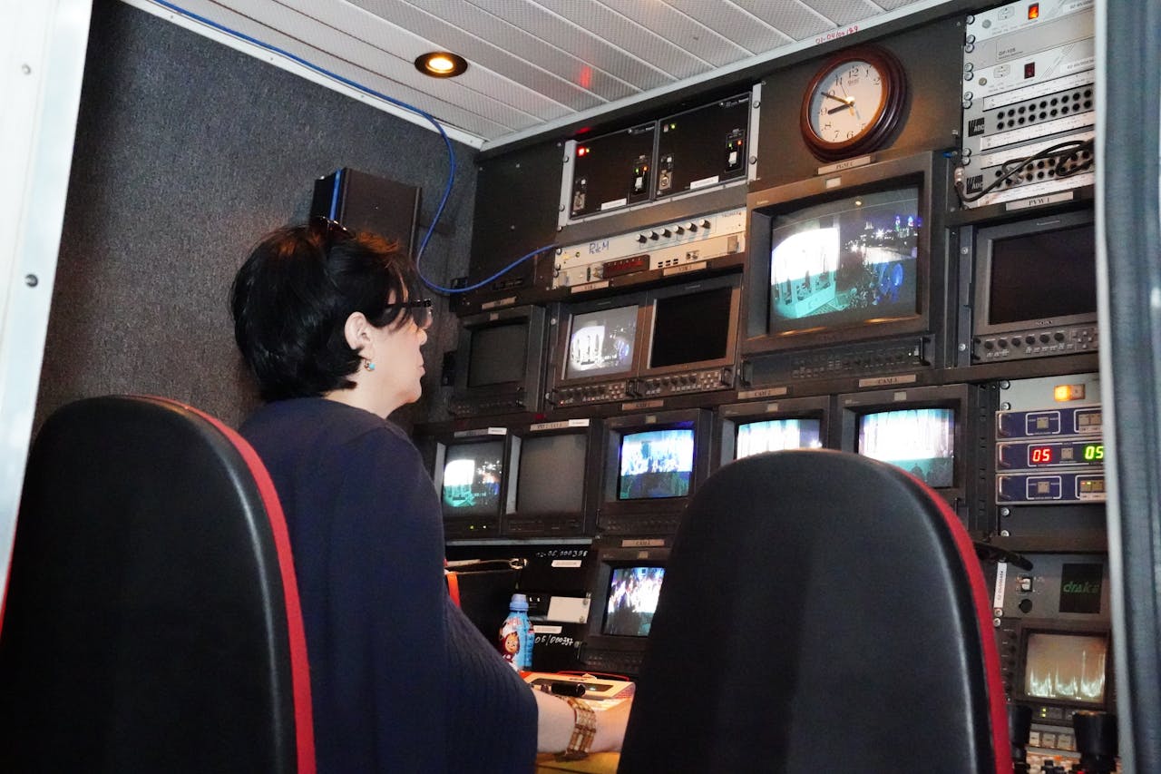 A simple broadcast studio or control-room image with screens and equipment.