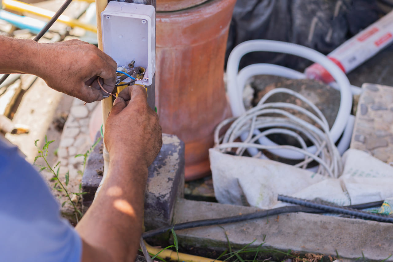 An electrician connecting wires to a detector base.
