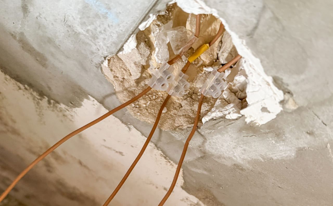 Exposed wall studs with new wiring routed through holes.