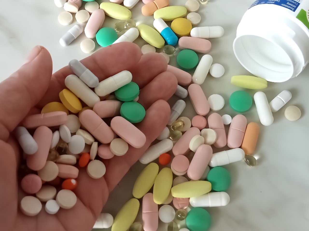 A hand holding expired pills near a toilet, showing a common but harmful disposal mistake.