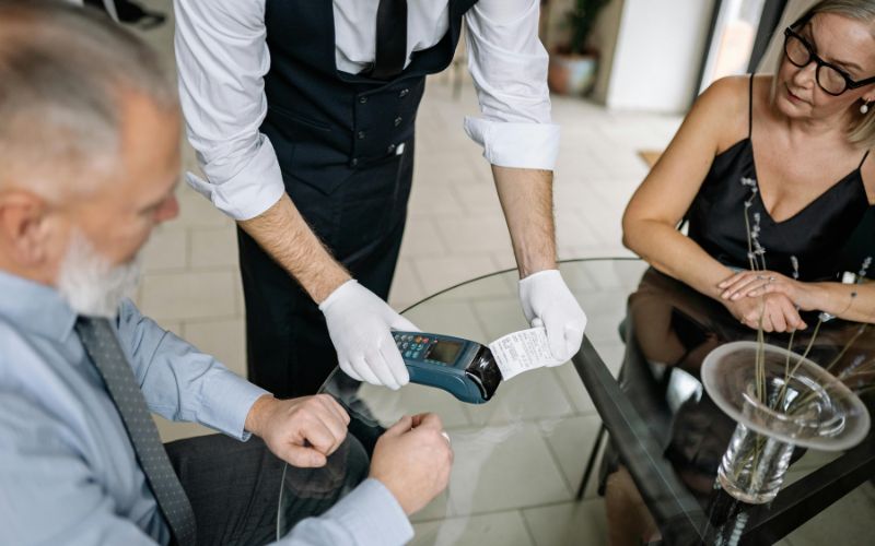 Cruise ship waiter receiving gratuity from guest at table