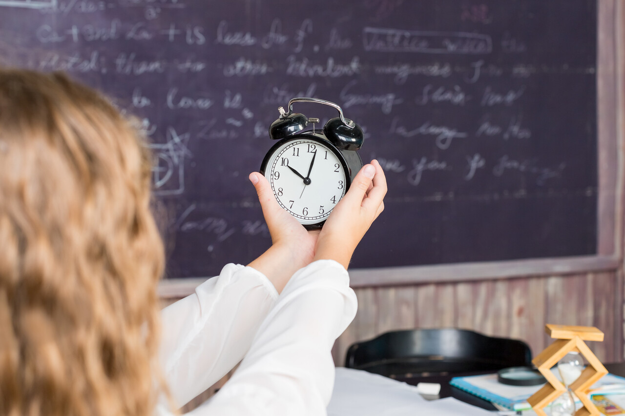 A child looking at a classroom wall clock or using a teaching clock.