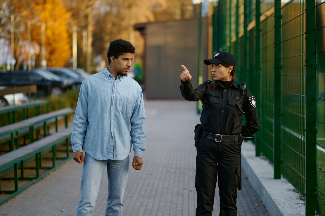 Person walking alone on a street with an officer in the background.