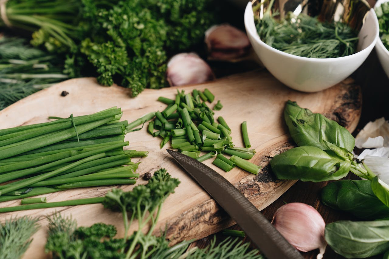 Fresh fennel fronds, sorrel, and lovage herbs on a wooden cutting board.