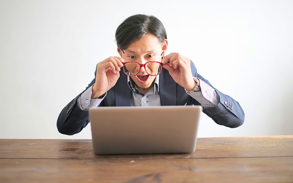 Traveler looking shocked at unexpected vacation bills while checking laptop and receipts