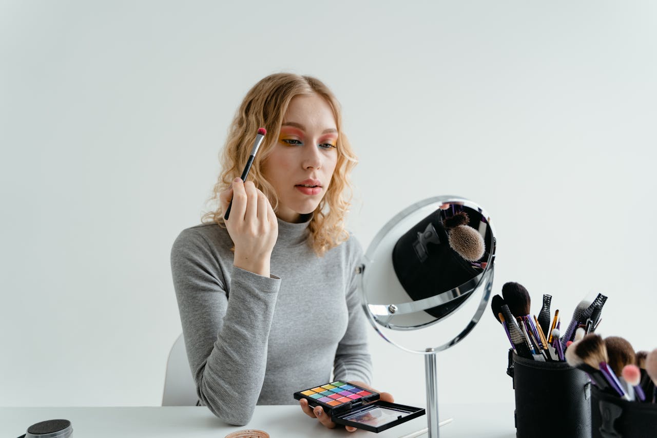 Individual applying hair dye at home while scissors sit ready for cutting