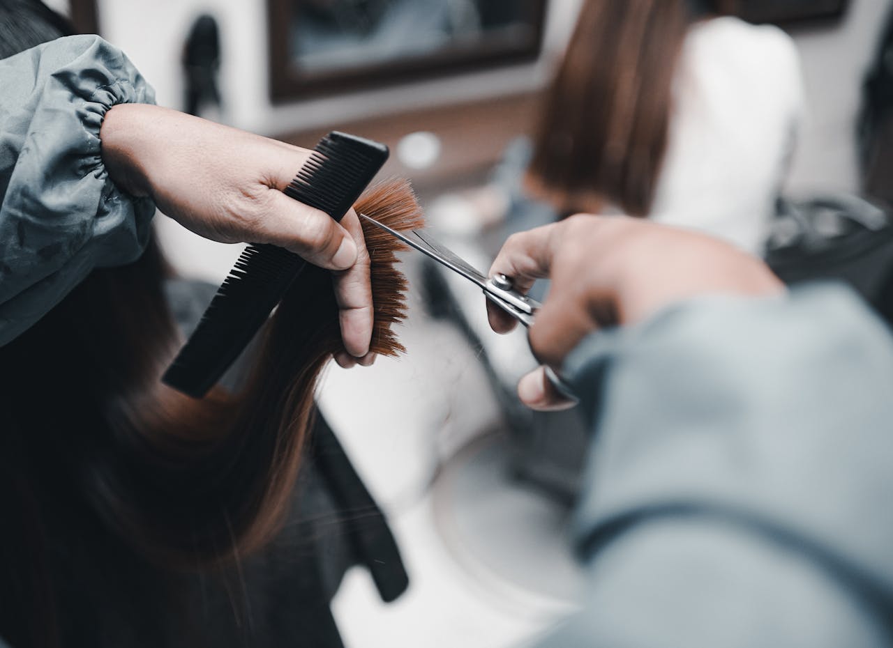 Person checking the back of their hair with handheld and wall mirrors