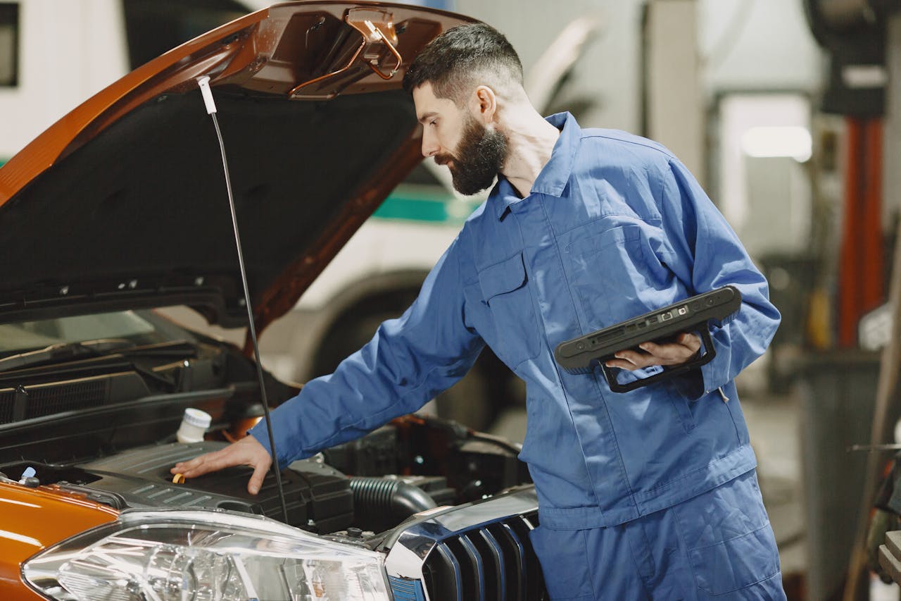 Mechanic using a diagnostic tool on a car in a modern repair shop, with the hood open and the car elevated on a lift, indicating professional tire inspection.