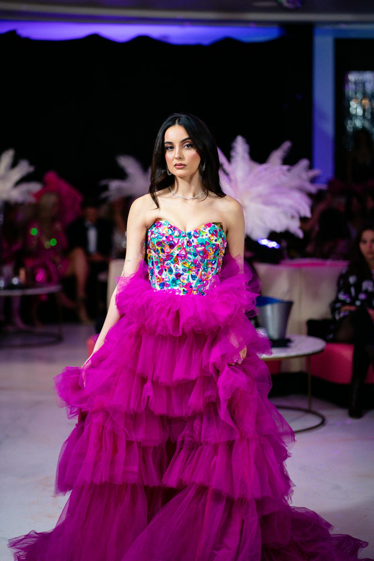 Celebrity wearing a vibrant fuchsia gown with clean lines, standing among other attendees, showcasing how bold color adds energy to the red carpet.