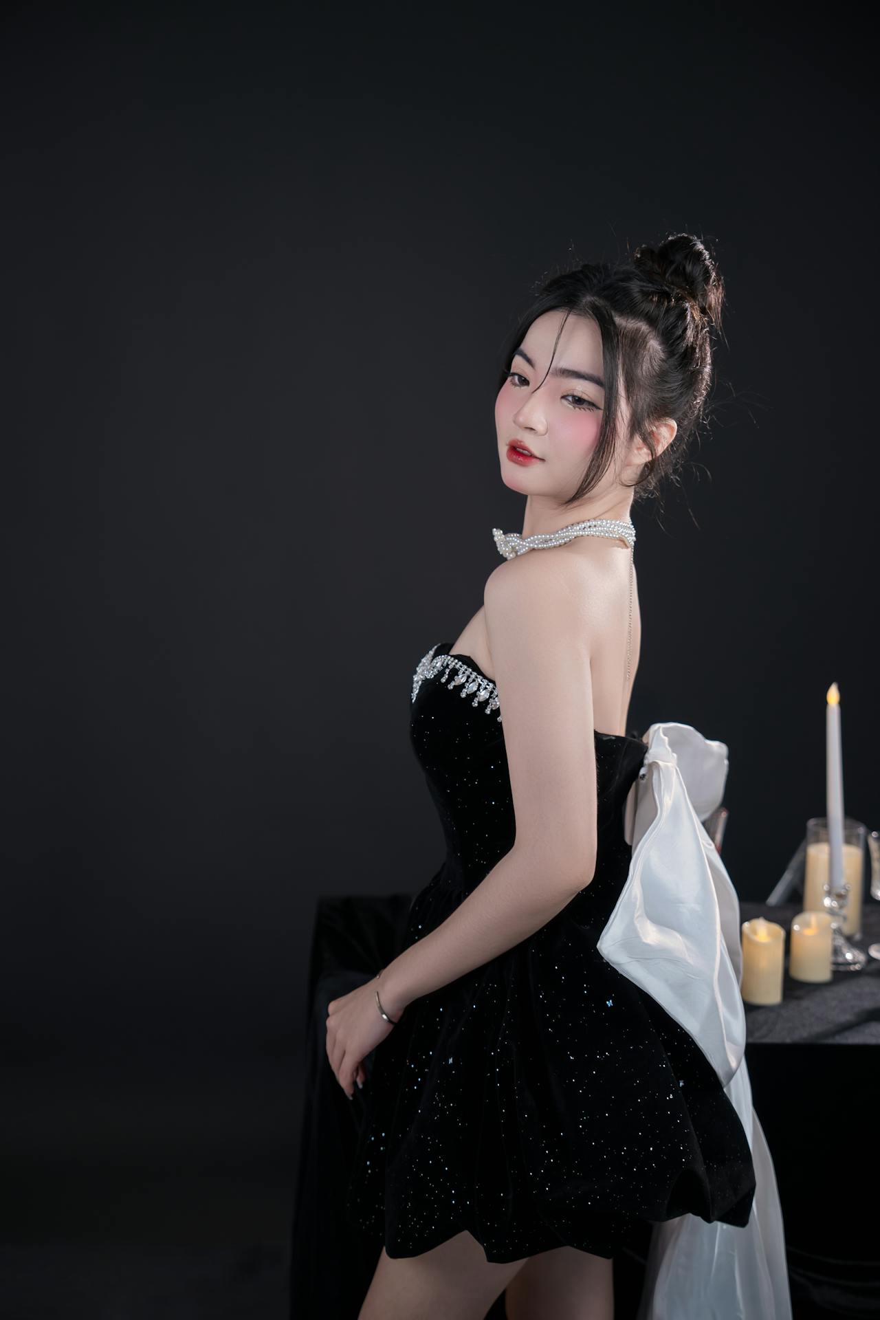 Attendee in a sleek black gown featuring cutouts and asymmetrical hem, paired with metallic accessories, demonstrating a modern update to classic black formalwear.