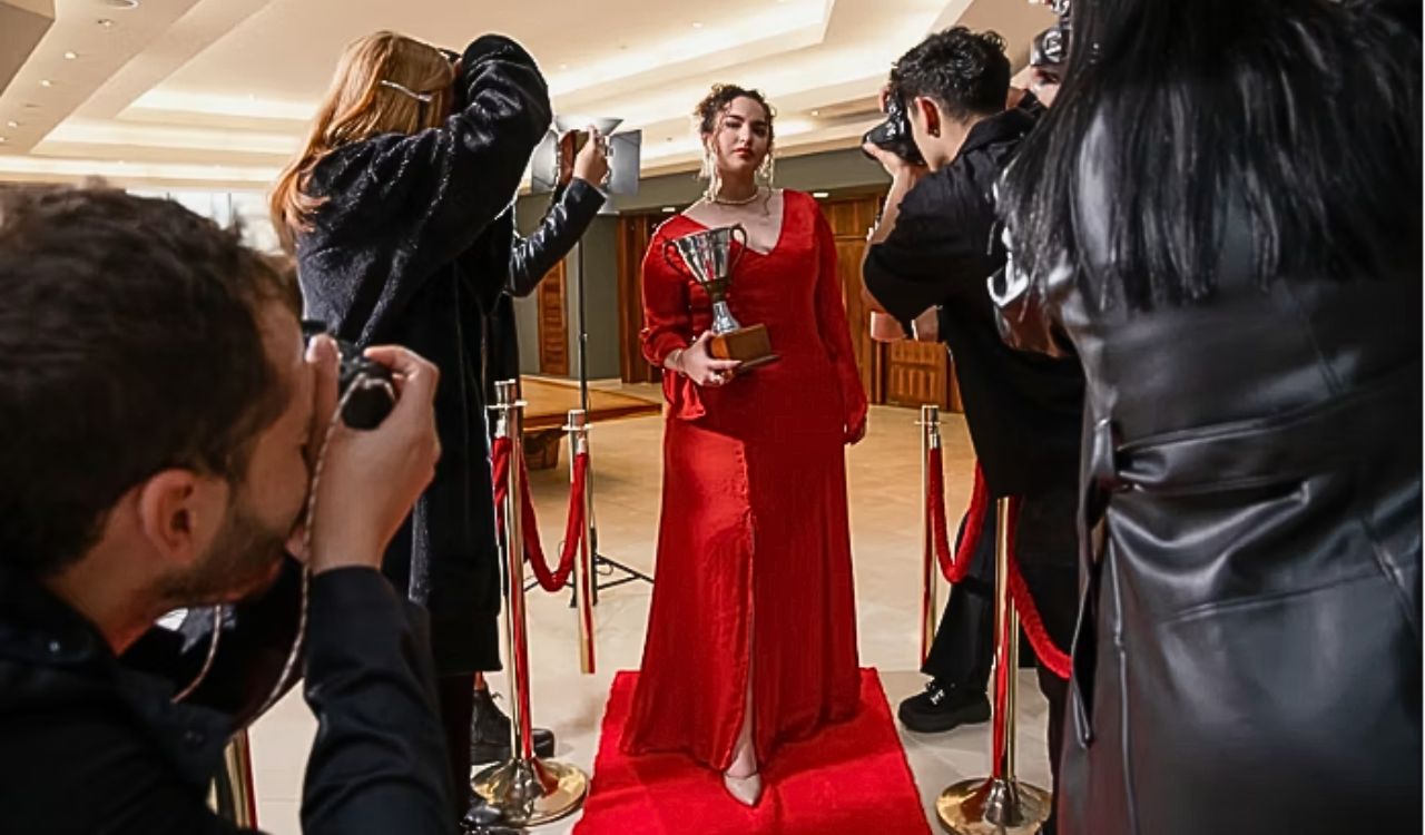 Celebrity wearing a gown with oversized sleeves and a dramatic train, walking confidently on the red carpet, showing a bold and sculptural silhouette.