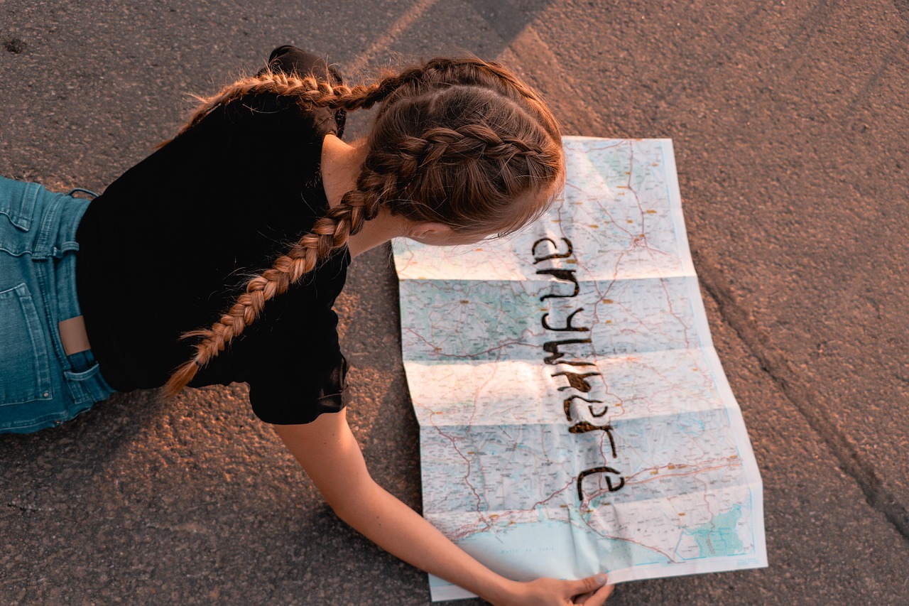 A child holding a simple paper map outdoors, pointing at directions.