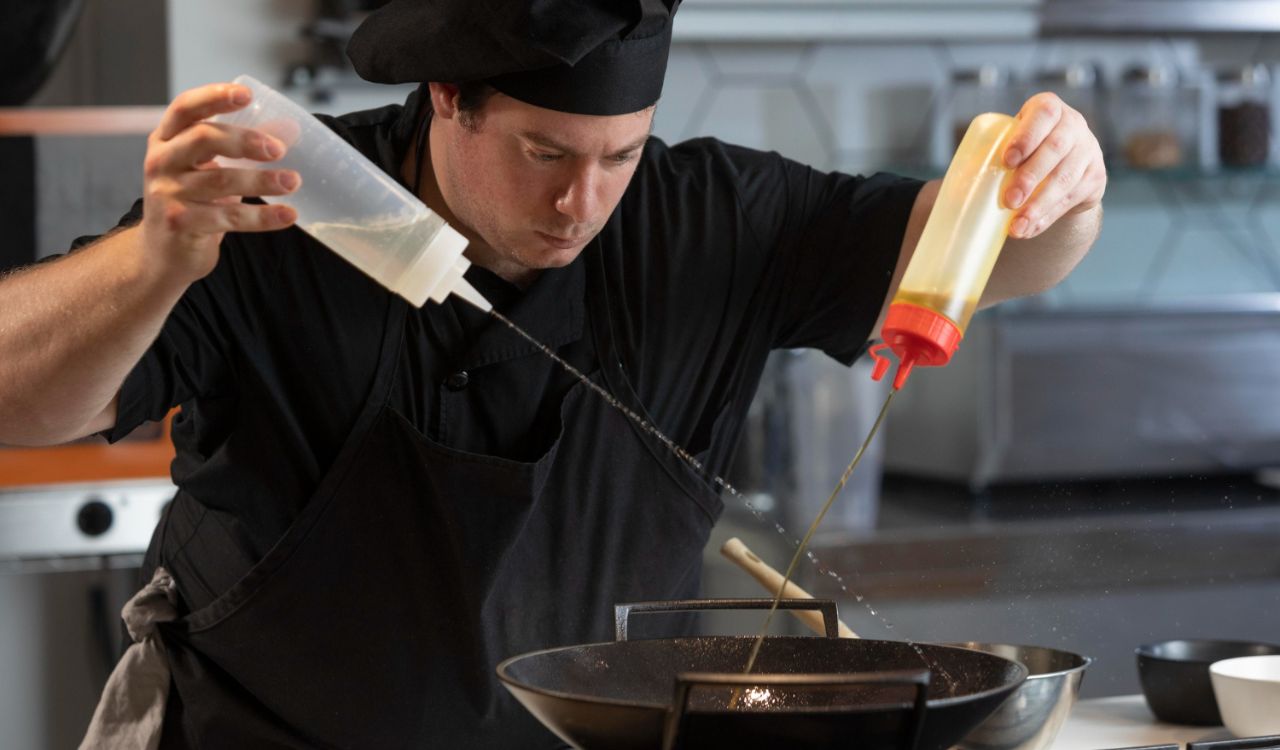 Chef tasting sauce to adjust seasoning in a restaurant kitchen.