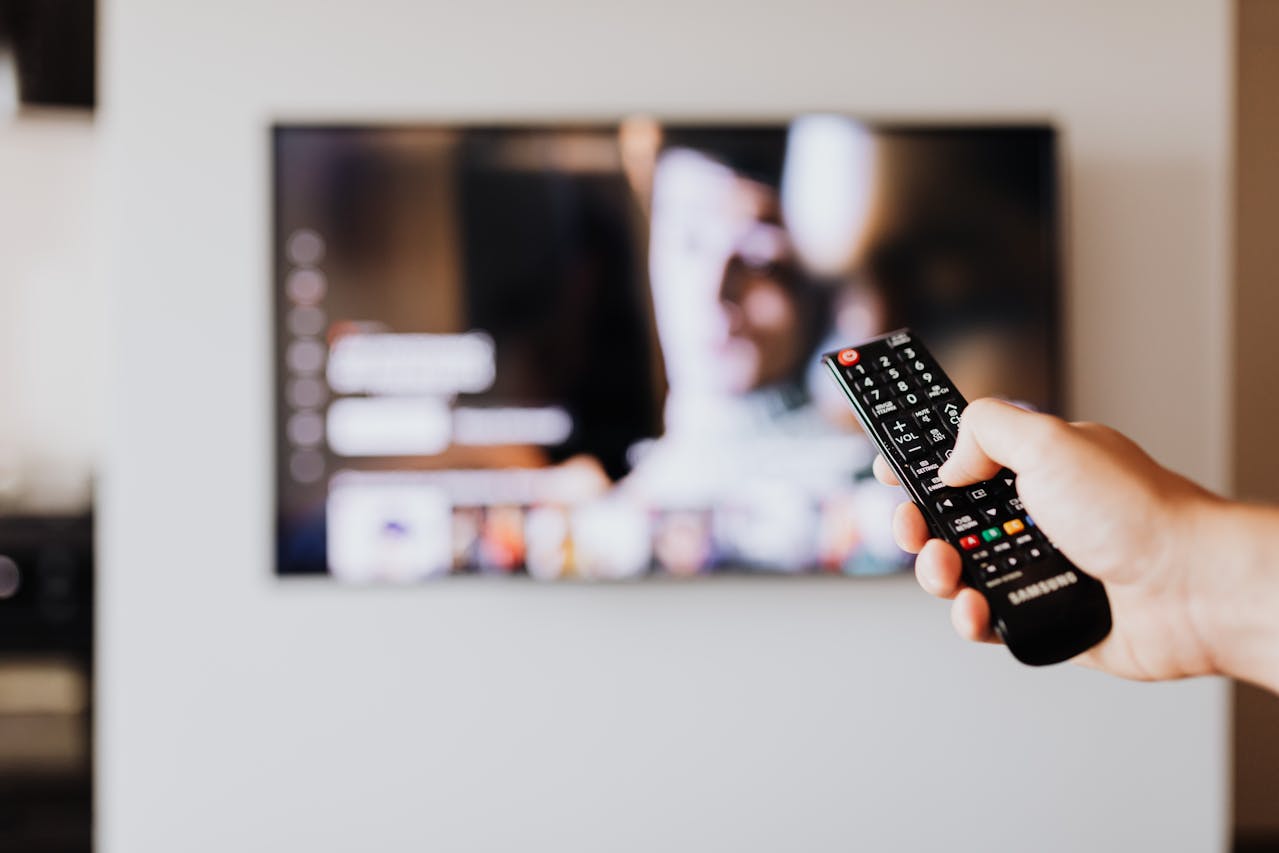 Remote control and TV showing a streaming platform menu on a living room couch