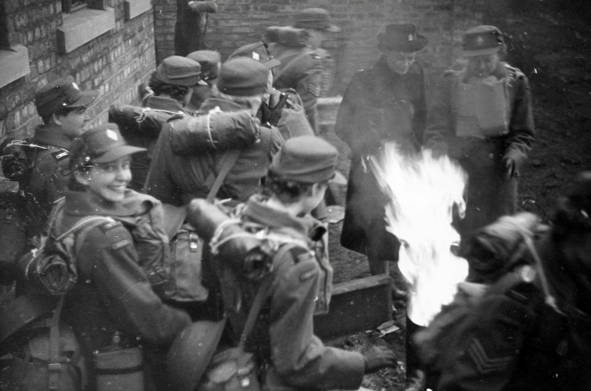Women working at a makeshift outdoor switchboard station under wartime conditions, showing focus and determination