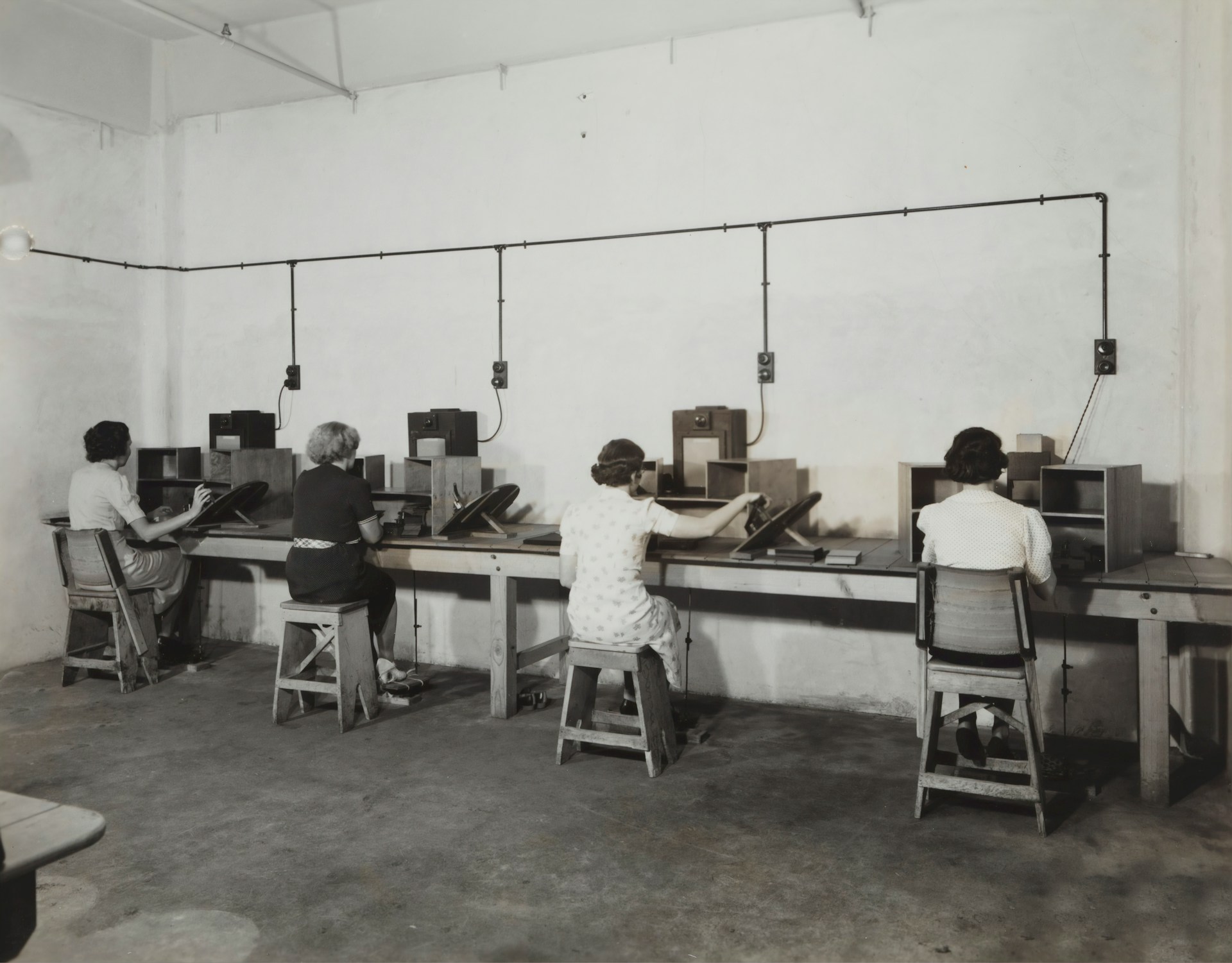 Women practicing rapid telephone switching and message routing in a training room with headsets and cords