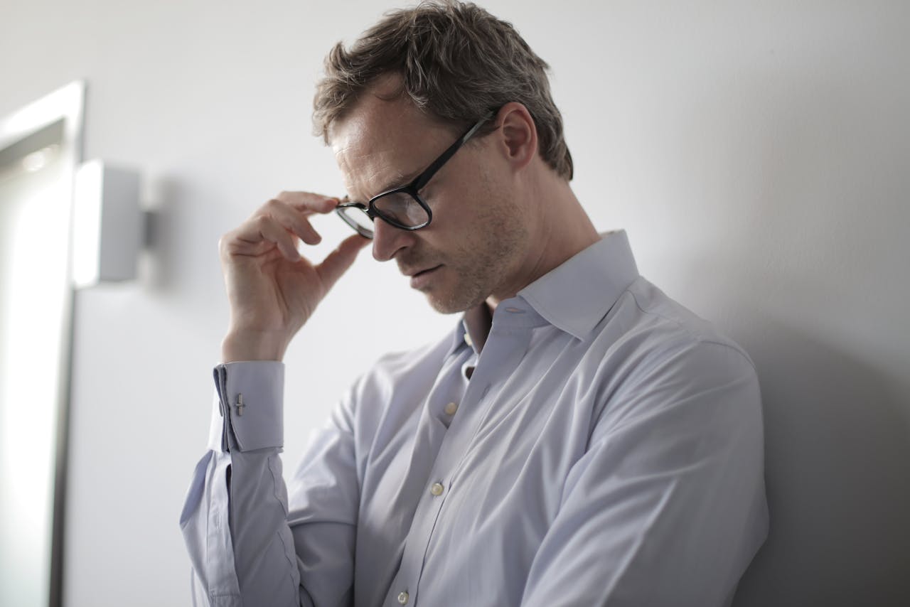 Man wearing eyeglasses looking thoughtfully, suggesting learning or understanding scam information