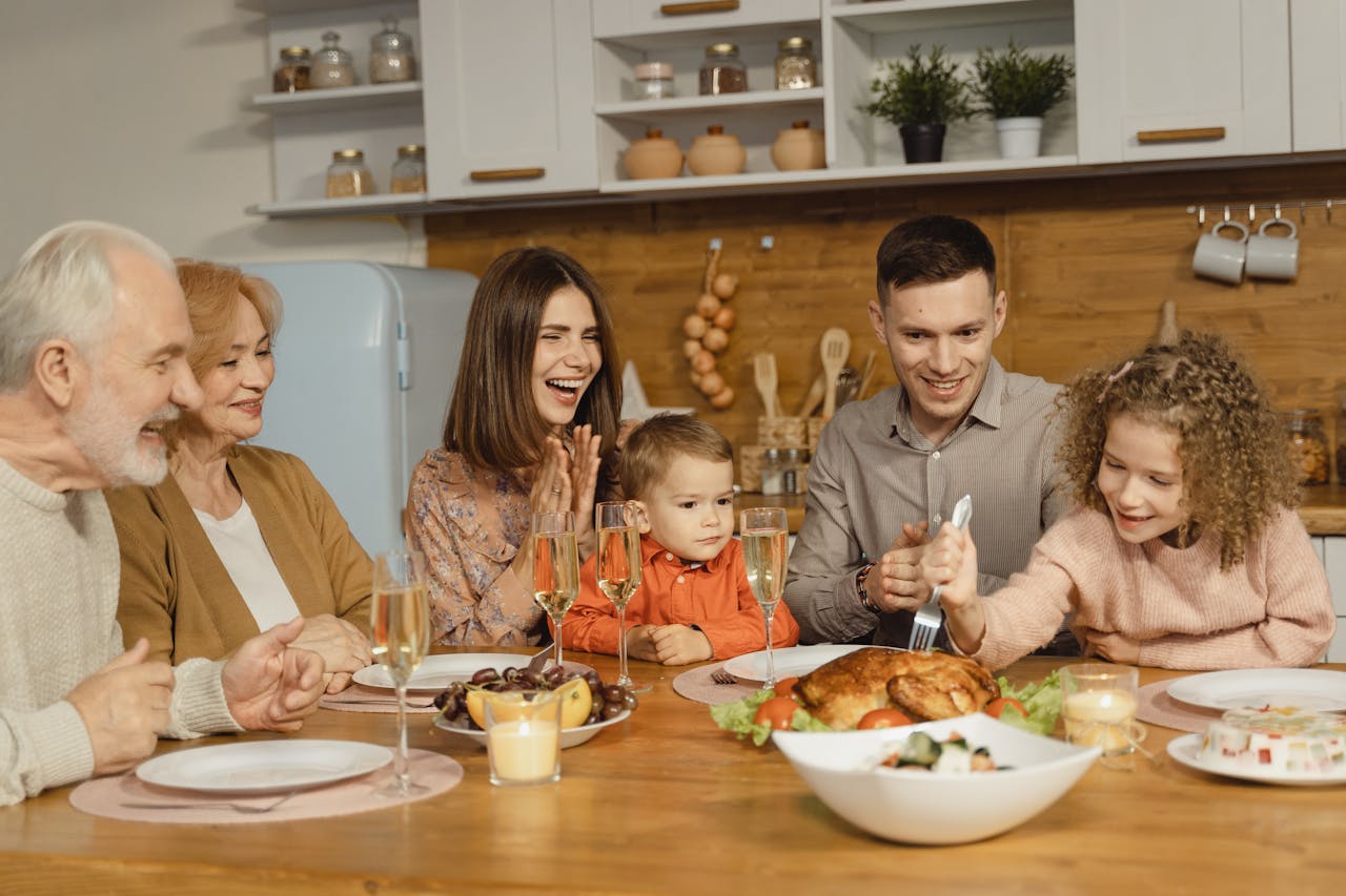 Family sitting at a table for a Thanksgiving dinner with turkey, sides, and smiling faces