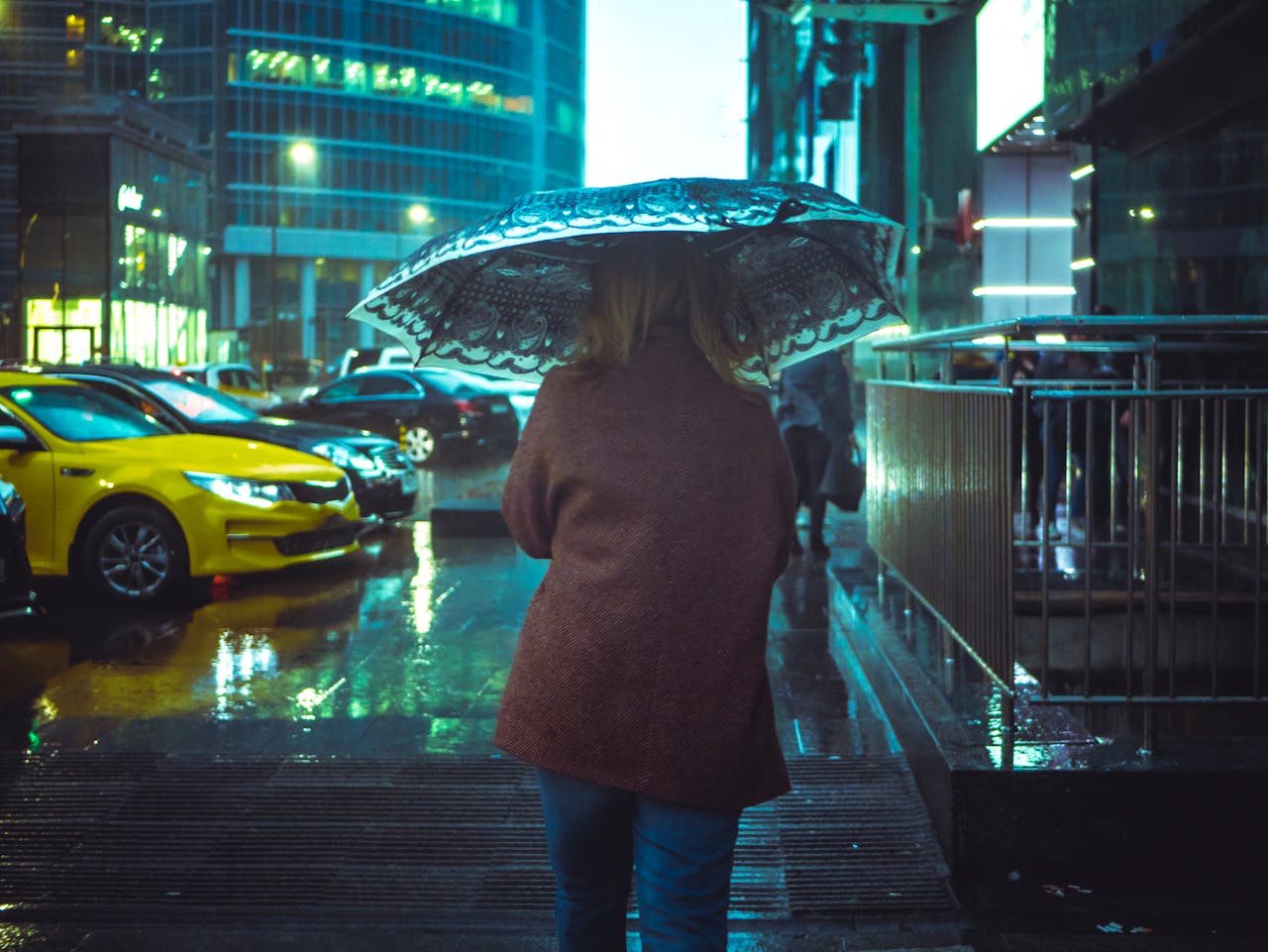 Traveler standing under umbrella in light tropical rain, showing that rainy season travel can still be enjoyable.