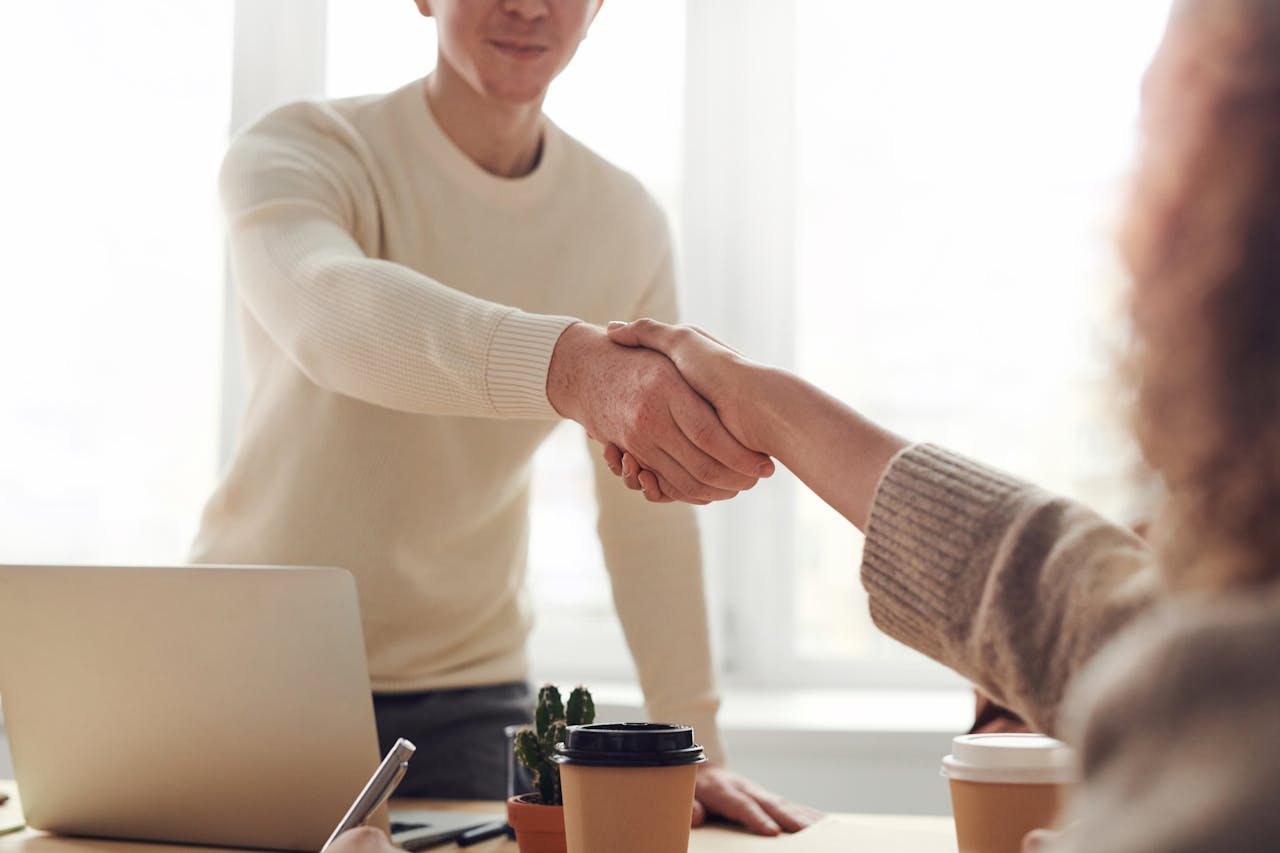Two people shaking hands with one person’s grip visibly weak, while maintaining awkward eye contact.