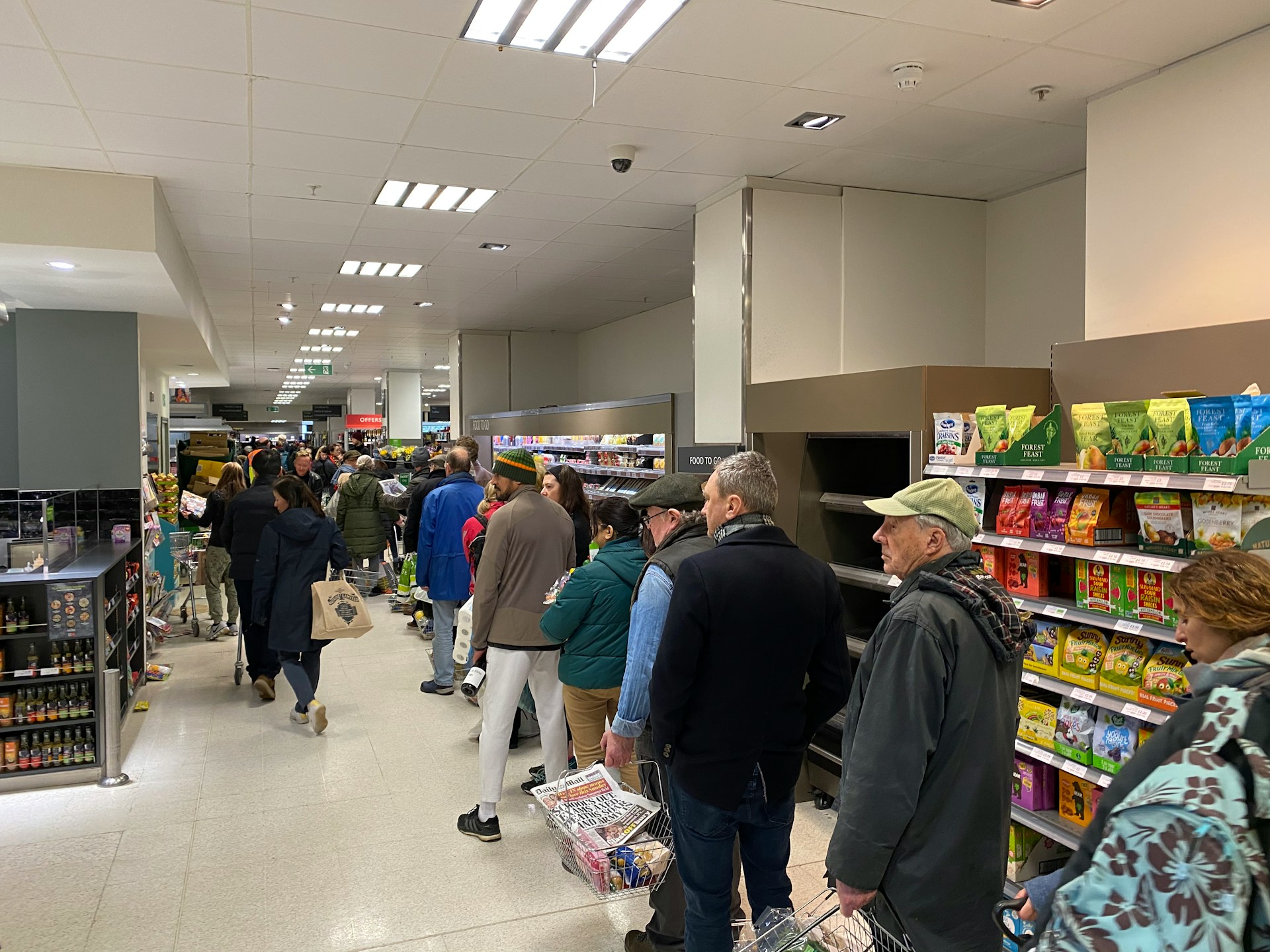 Shoppers standing closely together in a supermarket checkout line