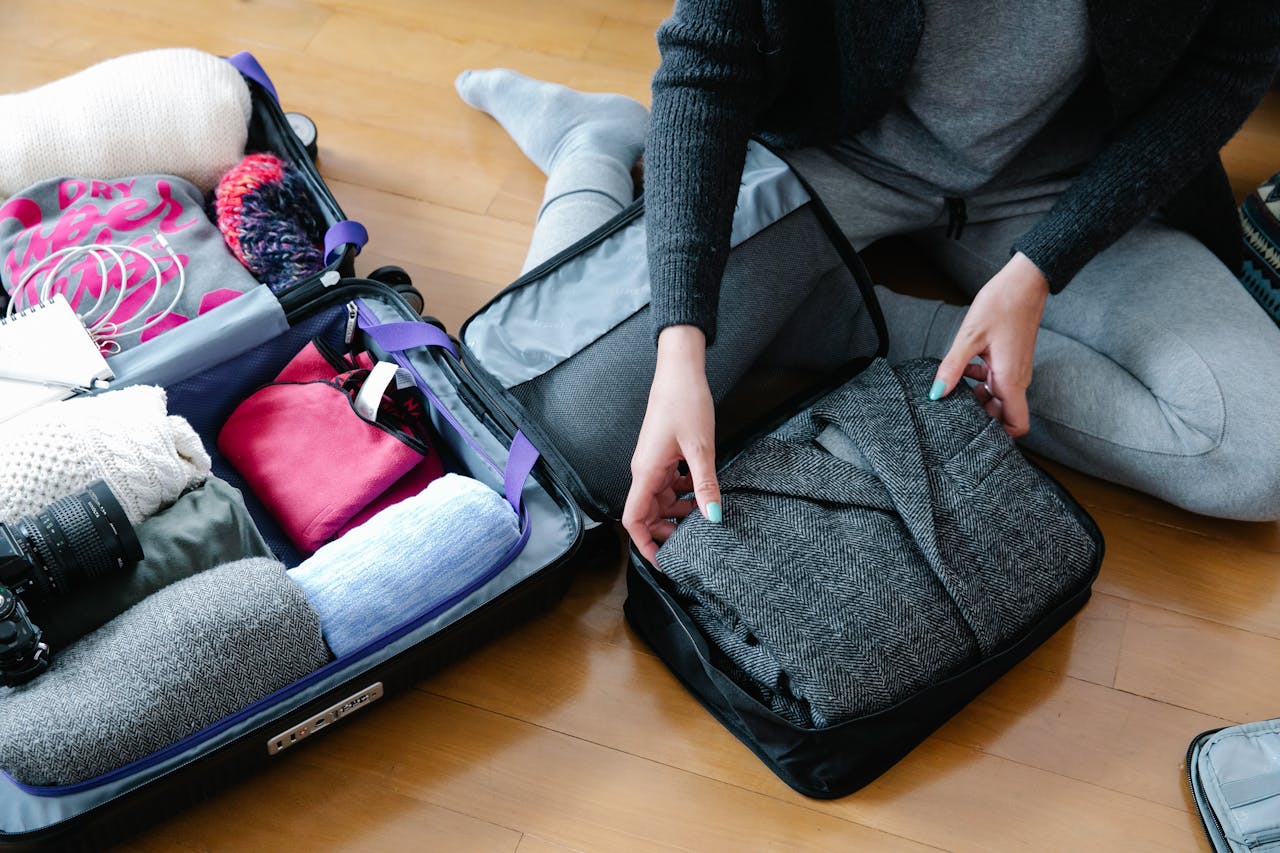 Lightweight jacket folded on top of a packed carry-on with other essentials visible.