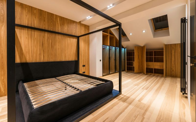 Bedroom featuring light wood paneling behind bed