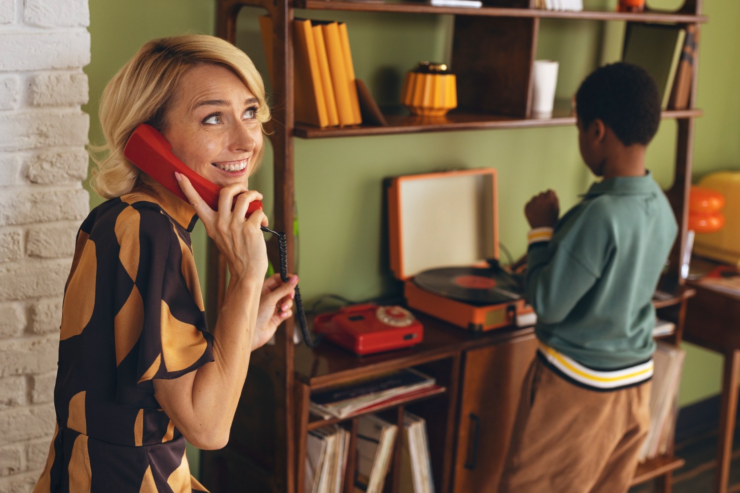 Person monopolizing rotary phone while others wait nearby.
