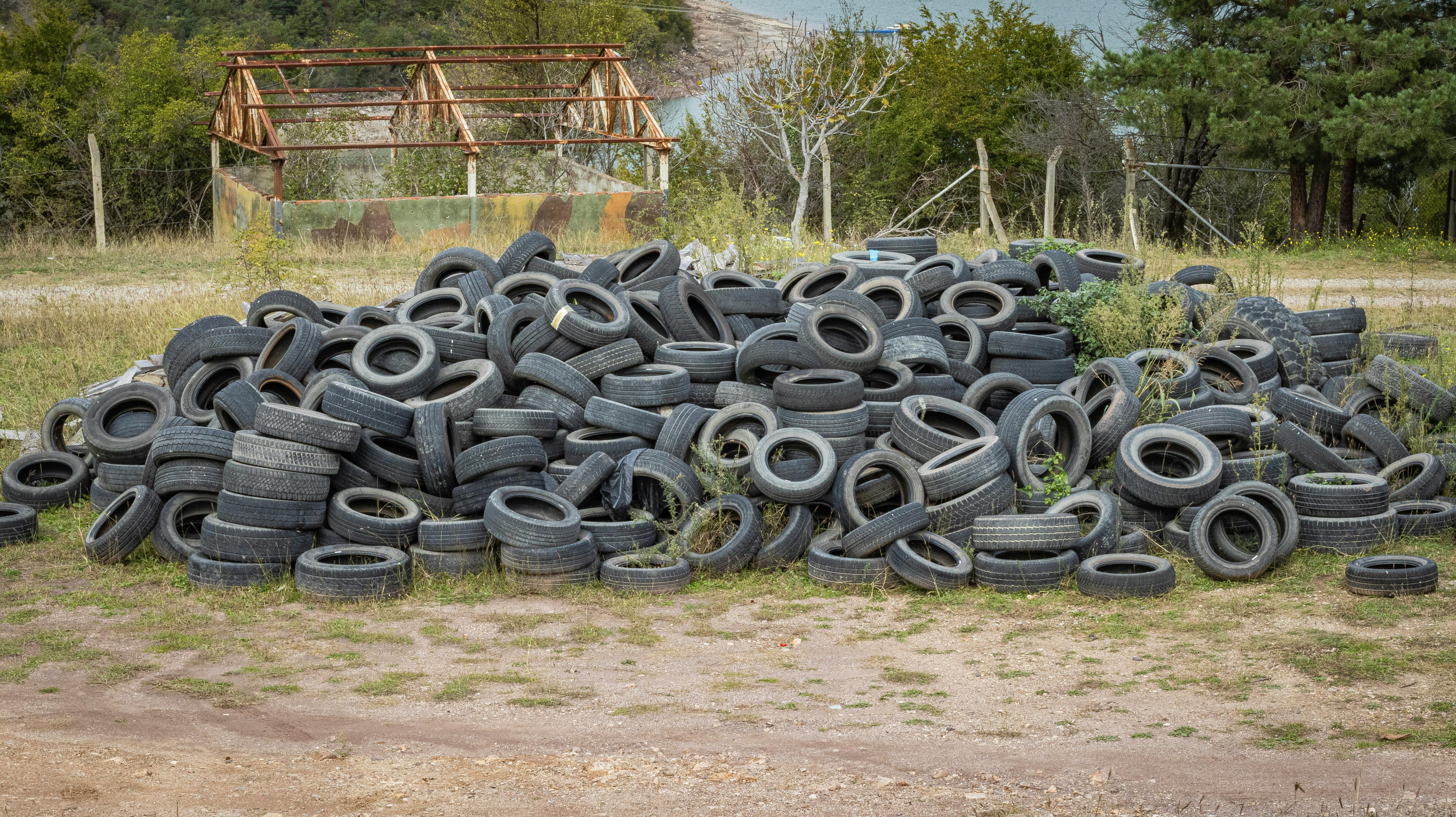 Old tires, appliances, and electronics at a recycling center, illustrating proper disposal of non-biodegradable waste.