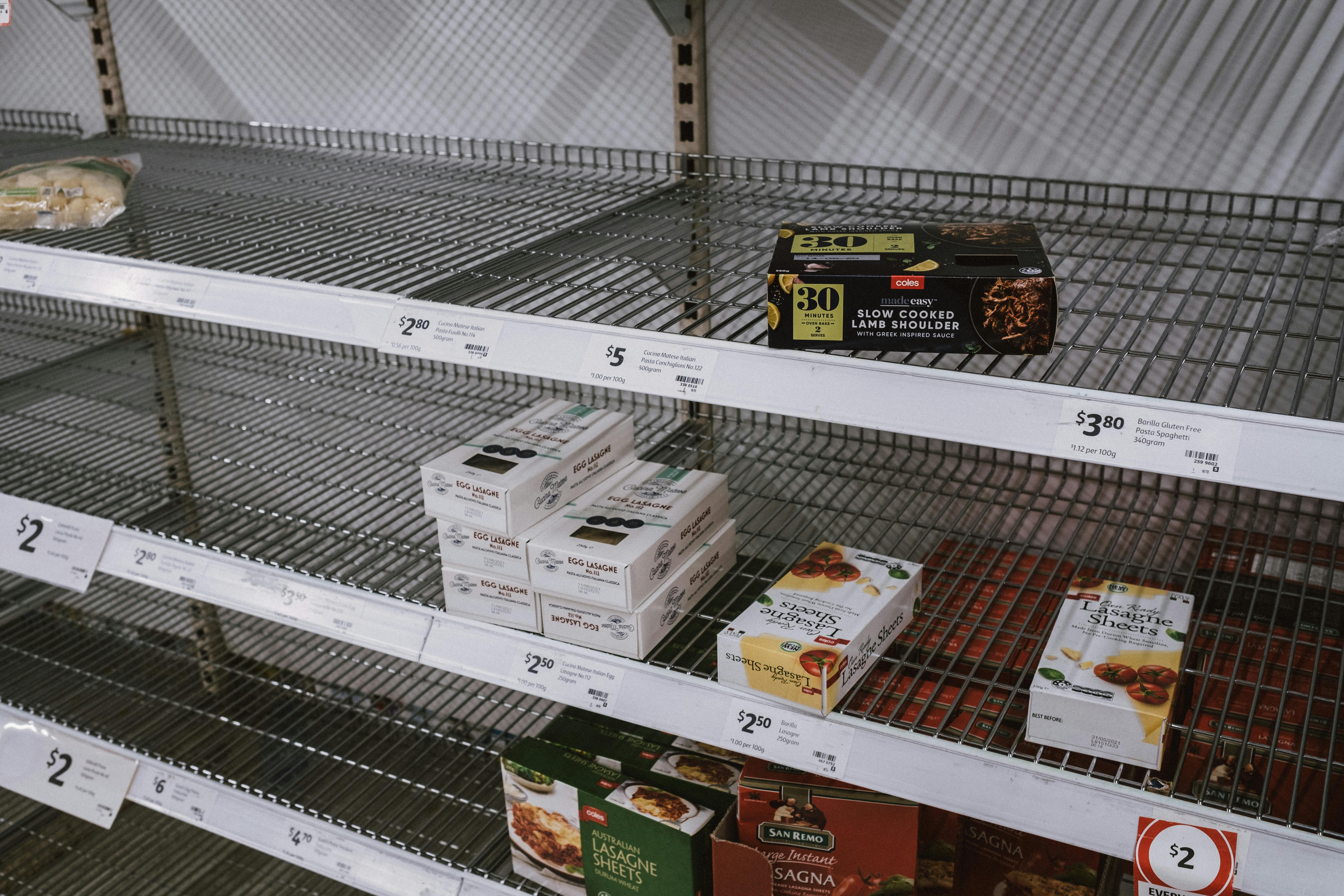 Partially empty grocery store shelves showing many sold‑out products and low stock.