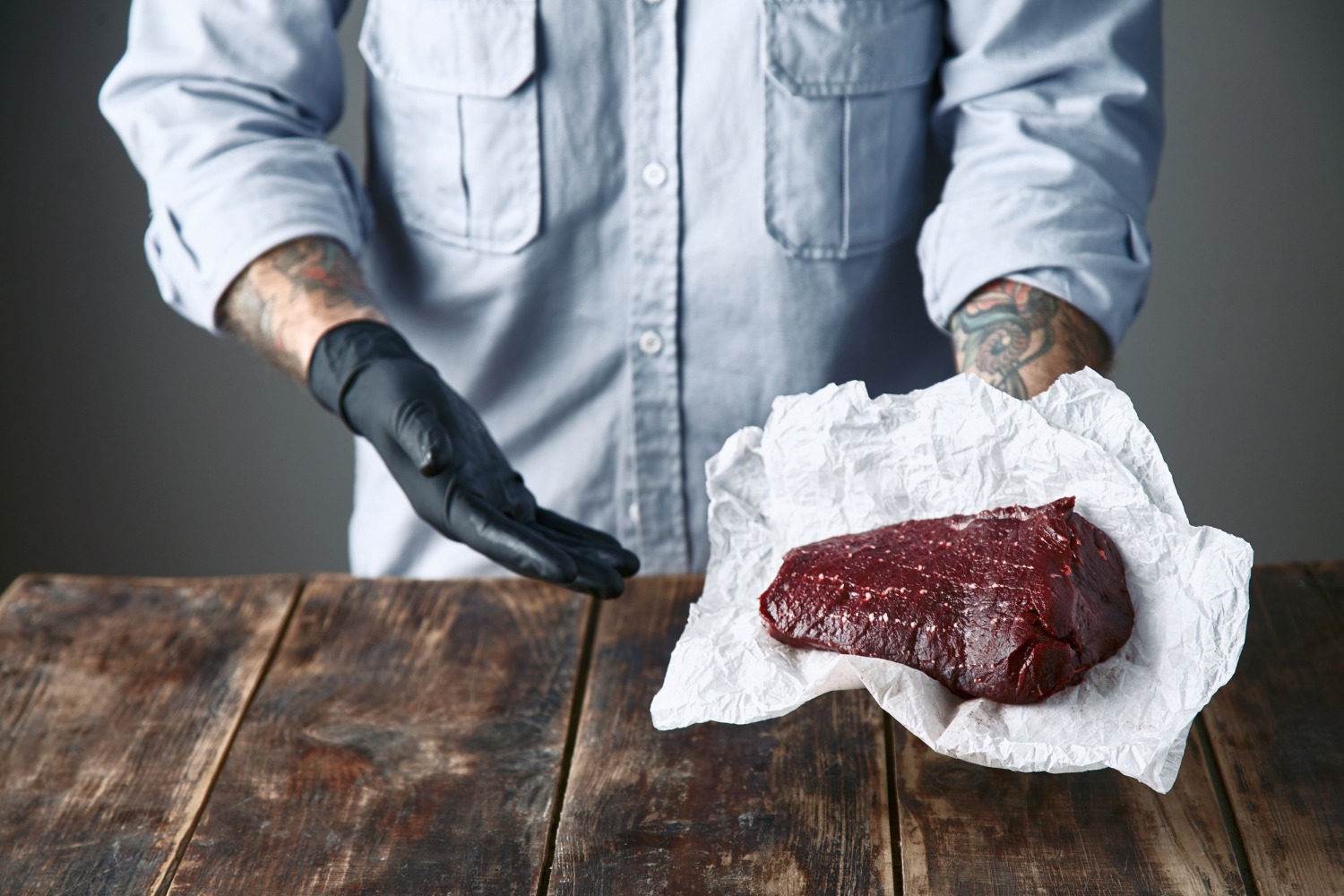 Patting a raw steak dry with paper towels to ensure proper sear